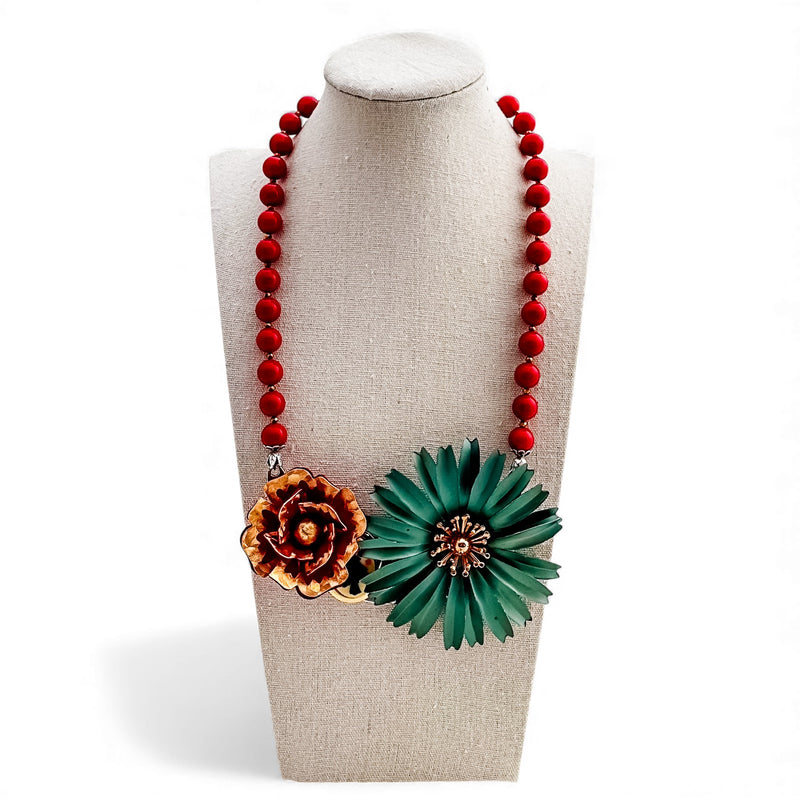 Necklace with red beads and floral pendants on a mannequin bust.