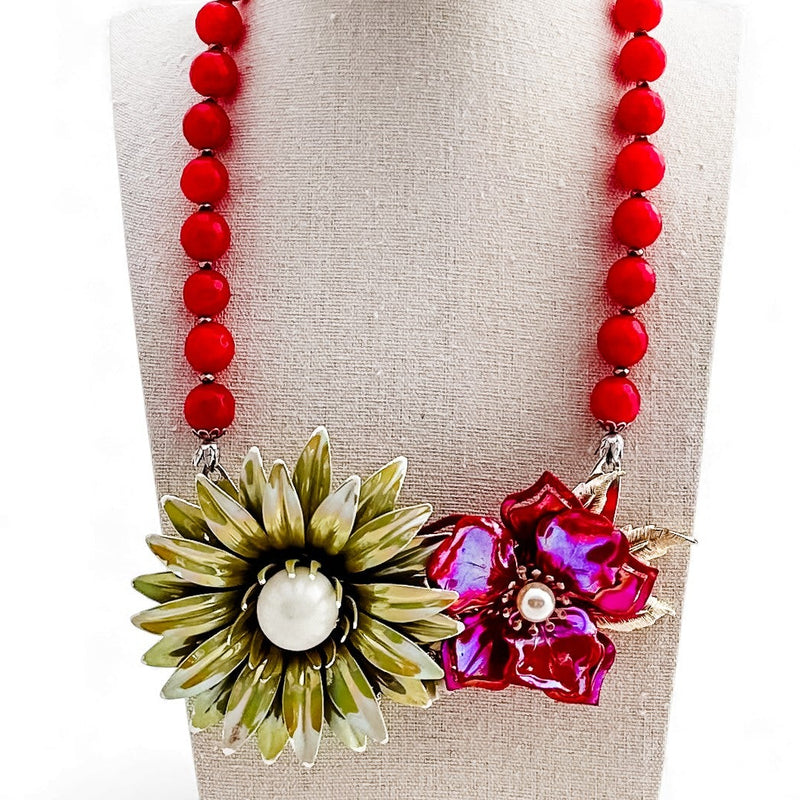 Necklace with red beads and floral pendants on a mannequin bust.