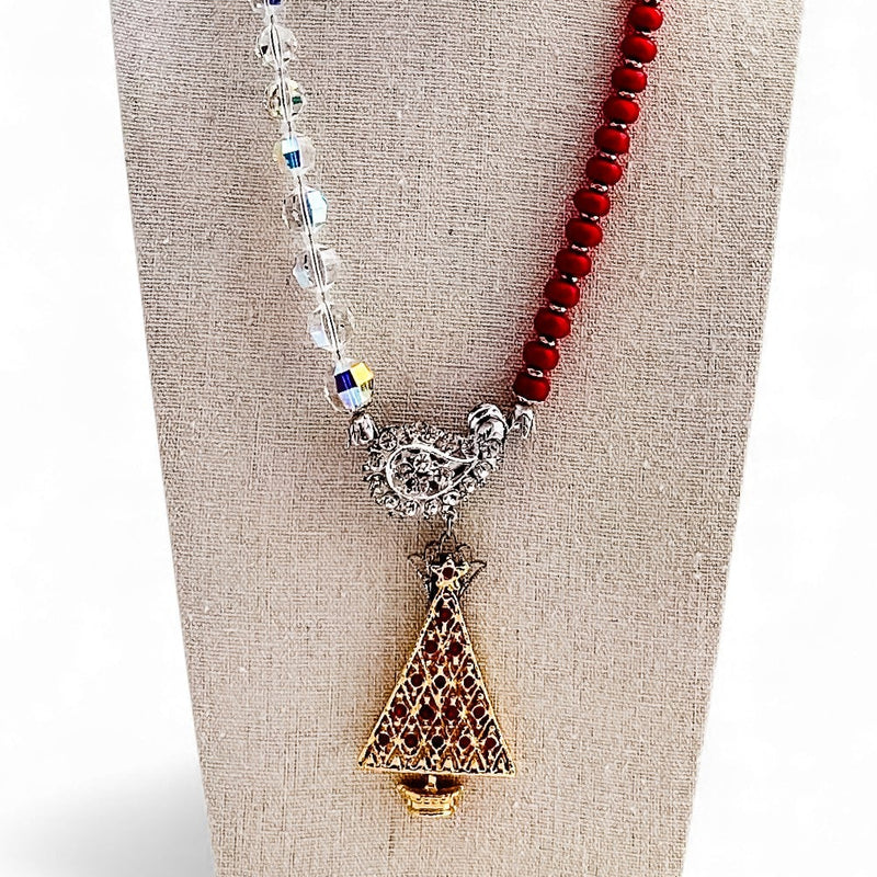 Necklace with red beads and a decorative pendant on a mannequin bust.