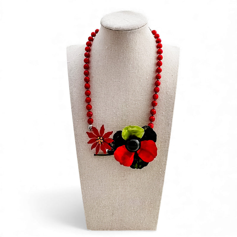 Necklace with red beads and floral pendant on a mannequin bust.