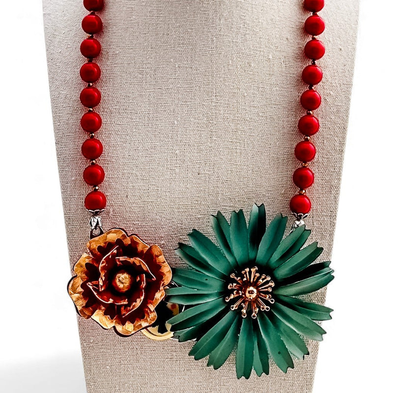 Necklace with red beads and floral pendants on a mannequin bust.