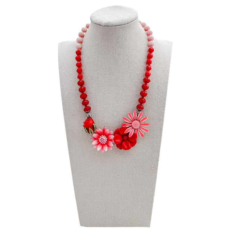 Necklace with red and pink floral beads on a mannequin bust against a white background