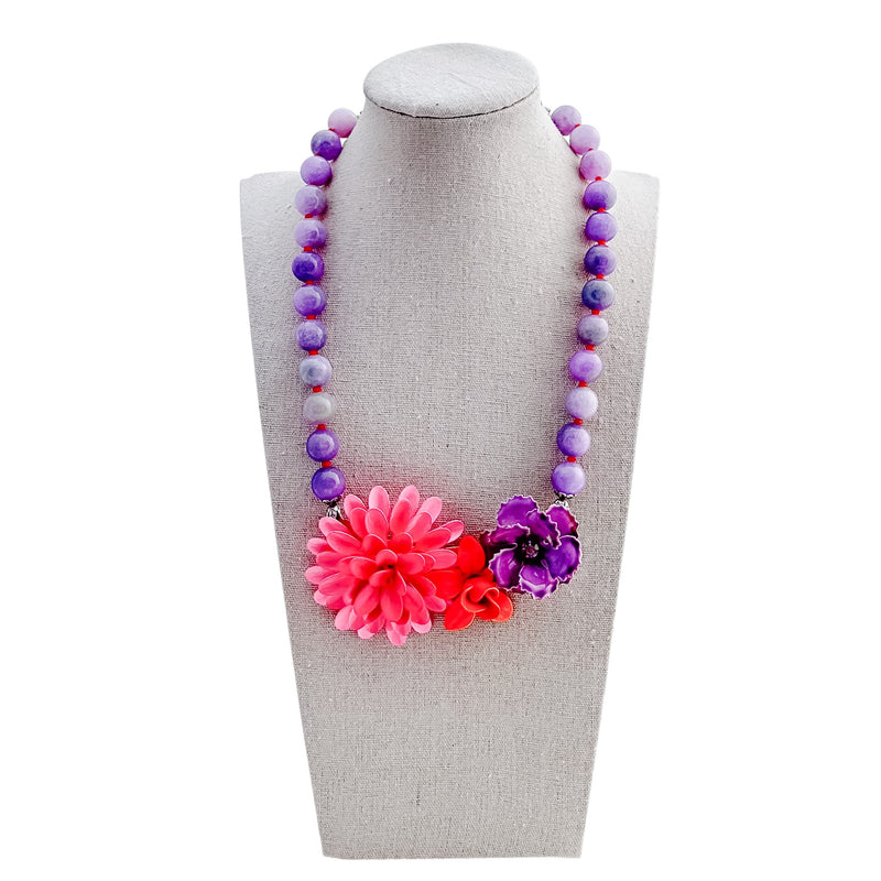 Necklace with colorful beads and flowers on a mannequin bust against a white background