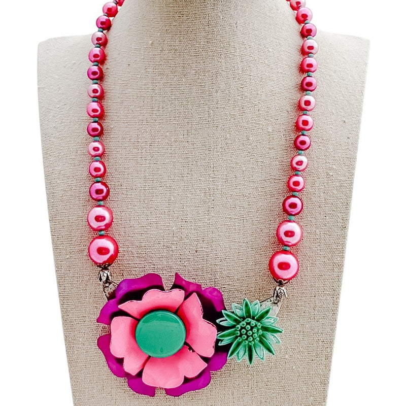 Necklace with pink beads and a floral pendant on a mannequin bust.