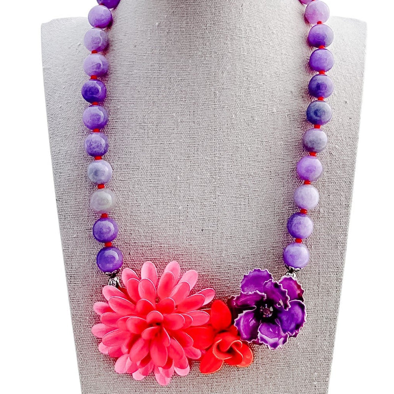 Necklace with colorful beads and flowers on a mannequin bust against a white background