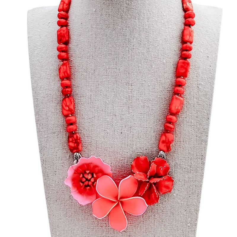Red beaded necklace with pink floral pendants on a gray mannequin bust.