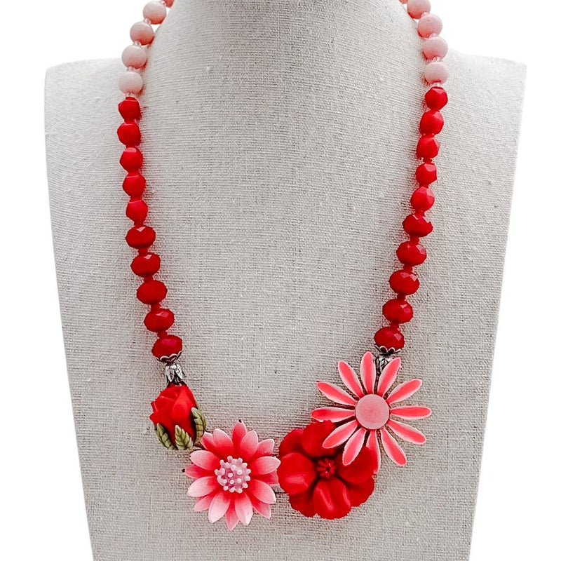 Necklace with red and pink floral beads on a mannequin bust against a white background